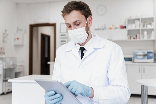 Doctor wearing mask with tablet, representing eCOA in clinical trials.